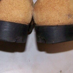 K&ouml;nnte beinhalten: Nahaufnahme der Unterseite von zwei braunen Wildlederschuhen mit schwarzen Gummisohlen.