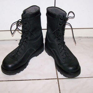 May include: A pair of black combat boots with a lace-up design. The boots have a sturdy sole and a high-top design, suitable for rugged use. The boots are made of a durable material and are designed for protection and support.