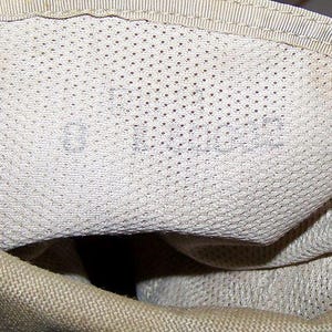 K&ouml;nnte beinhalten: Nahaufnahme des Innenraums einer beige Canvas-Tasche mit Mesh-Futter. Das Futter hat ein kleines, verblasstes Etikett mit der Aufschrift "01-10-92".