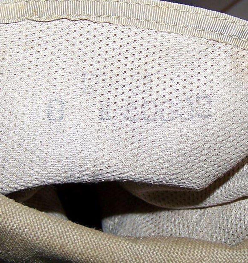 K&ouml;nnte beinhalten: Nahaufnahme des Innenraums einer beige Canvas-Tasche mit Mesh-Futter. Das Futter hat ein kleines, verblasstes Etikett mit der Aufschrift "01-10-92".