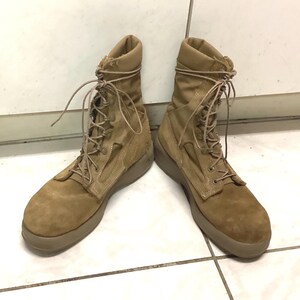 Puede incluir: Un par de botas de combate color canela con cordones. Las botas tienen una textura similar a la gamuza en la puntera y un material similar a la lona en la caña. Las suelas son de color canela a juego.