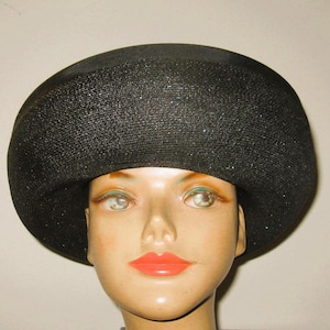 May include: A black wide-brimmed hat with a sparkly texture. The hat is worn by a mannequin with a neutral expression.