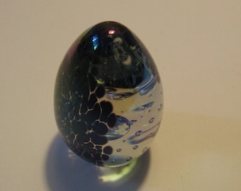 May include: A glass egg paperweight with a black and white patterned design and iridescent bubbles inside.
