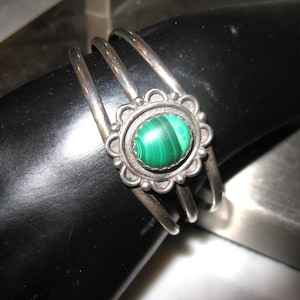 May include: A silver bracelet with a green malachite stone set in a floral design.