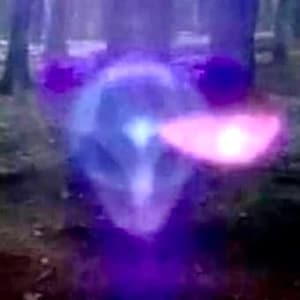 K&ouml;nnte beinhalten: Eine wirbelnde blaue und violette Kugel, aus der ein helles pinkfarbenes Licht strahlt. Die Kugel ist von einem verschwommenen Hintergrund aus B&auml;umen umgeben.