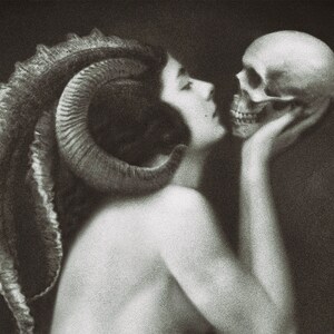 May include: A black and white artistic print featuring a profile view of a figure with large, curved ram horns extending from the head. The figure is shown from the shoulders up, leaning forward to touch a human skull held in their hand.