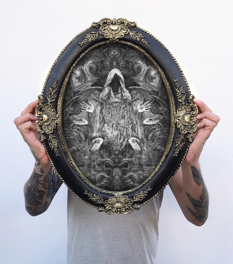 May include: An oval-shaped wall art piece featuring a black and white intricate illustration of a hooded figure surrounded by multiple hands and wings, encased in a decorative black frame with ornate gold-colored filigree accents at the edges.