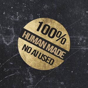 Może przedstawiać: Okrągła naklejka ze złotej folii z czarnym napisem 100% HUMAN MADE NO AI USED. Naklejka ma teksturowane, metaliczne wykończenie i znajduje się na ciemnym, postarzanym antracytowym tle z widocznymi zarysowaniami i niedoskonałościami powierzchni.