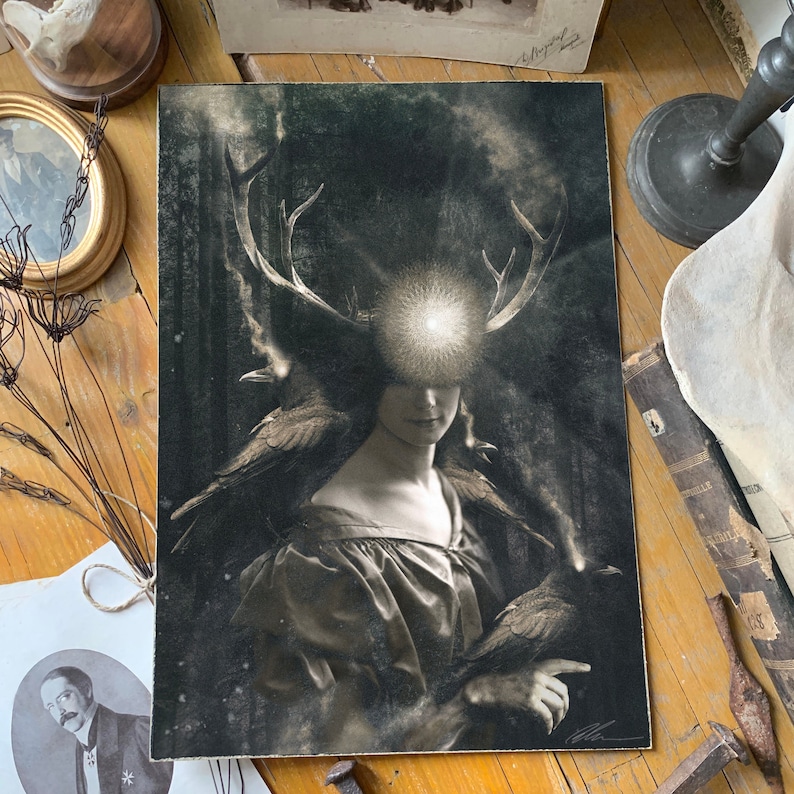 May include: A rectangular art print featuring a monochromatic portrait of a figure with large deer antlers and a glowing light source between them. Two dark birds are perched on the shoulders, set against a dark, textured forest background.