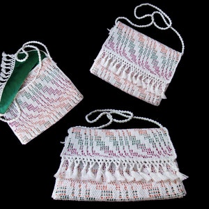 K&ouml;nnte beinhalten: Drei wei&szlig;e geh&auml;kelte Handtaschen mit bunten Mustern und Fransen. Die Handtaschen haben verstellbare Tr&auml;ger und sind aus einer filigranen H&auml;kelarbeit gefertigt.