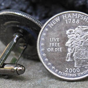 May include: A pair of cufflinks made from a silver-toned New Hampshire quarter. The quarter features the Old Man of the Mountain, a rock formation that was a popular tourist attraction in the state. The text on the coin reads "New Hampshire 1788", "Live Free or Die", "Old Man of the Mountain", and "E Pluribus Unum".