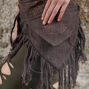 May include: A brown fabric belt with fringe detail. The belt is tied around the waist and has a woven design.