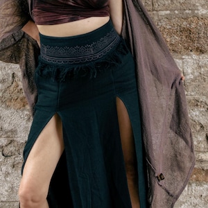 May include: A black maxi skirt with a high-waisted embroidered waistband and two slits at the front. The skirt is paired with a brown shawl.