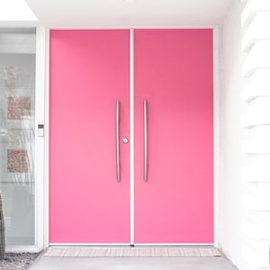 May include: A pair of bright pink double doors with silver handles. The doors are set in a white frame and are surrounded by white walls.