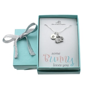 May include: A silver necklace with a small rabbit charm and a letter 'K' charm. The necklace is in a light blue gift box with a silver ribbon. The box has a card that says "some bunny loves you".
