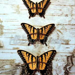 May include: Three yellow and black butterfly patches with glitter accents. The patches are arranged vertically on a white wood background.
