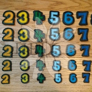 May include: Five rows of colorful felt patches with numbers 0 through 9. The patches are arranged in rows of ten, with each row featuring a different color scheme. The first row is red, the second is orange, the third is yellow, the fourth is green, and the fifth is blue.