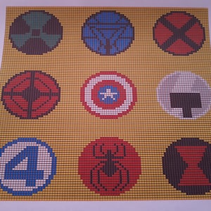 Può includere: Uno sfondo giallo con nove cerchi colorati, ognuno con un logo di supereroe diverso. I loghi includono Iron Man, Captain America, Thor, Hulk, Spider-Man, Vedova Nera, Occhio di Falco e i Fantastici Quattro.