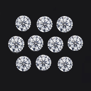May include: Ten round, clear, faceted diamonds on a black background.