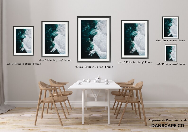 May include: A collection of framed art prints depicting an aerial view of ocean waves. The prints vary in size, with the largest being 36x24 inches in a 40x28 inch frame. The artwork features shades of teal and white, creating a dynamic contrast. The prints are displayed above a dining table.