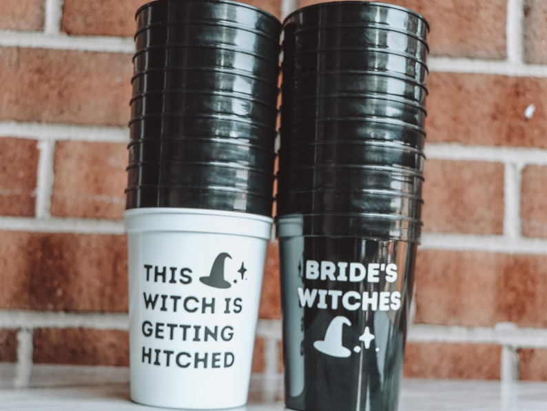 May include: A stack of black and white plastic cups. One stack of cups is white with the text "THIS WITCH IS GETTING HITCHED" and a witch hat graphic. The other stack is black with the text "BRIDE'S WITCHES" and a witch hat graphic.