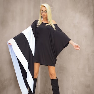 May include: A woman wearing a black and white striped off-the-shoulder dress with long sleeves and black knee-high boots.