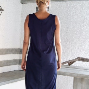 May include: A navy blue sleeveless midi dress with a high neckline and a slightly curved hemline.