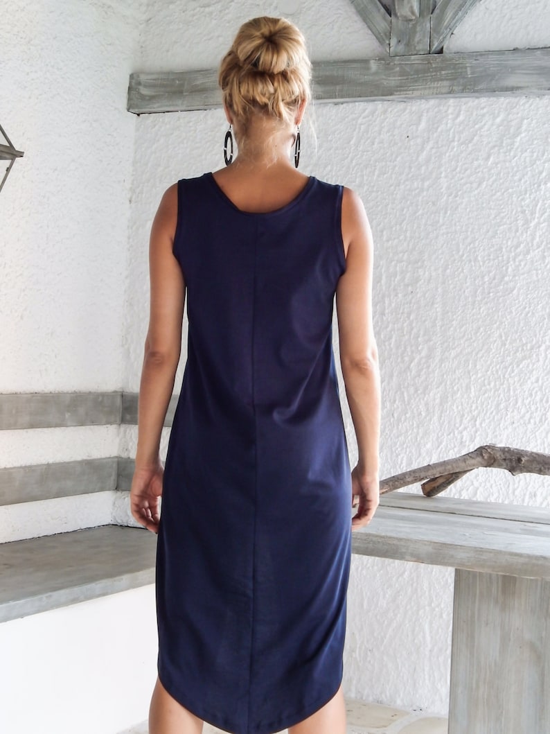 May include: A navy blue sleeveless midi dress with a high neckline and a slightly curved hemline.
