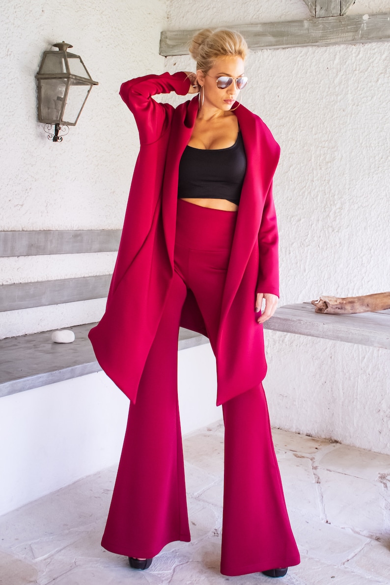 Op de afbeelding: Een vrouw draagt een magenta hoodie en een bijpassende wijde broek. De hoodie heeft een lang, vloeiend ontwerp en de broek heeft een uitlopende pasvorm.