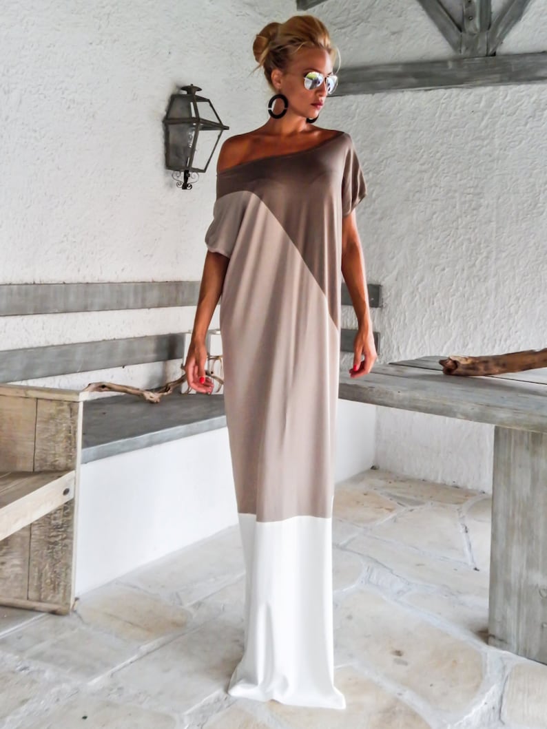 May include: A long, loose-fitting dress with a brown, beige, and white color block design. The dress has a scoop neckline and short sleeves.