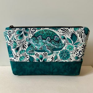 May include: A teal and white zippered pouch with a floral pattern and a green turtle design.