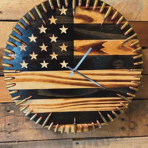 May include: A wooden clock with a distressed American flag design. The clock face is surrounded by bullet casings.