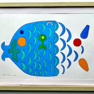 May include: A framed, colorful illustration of a fish. The fish is primarily blue with green, orange, and red accents. The artwork is in a light-colored wooden frame, and the fish design is whimsical and playful.