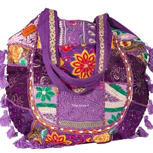 May include: A purple patchwork tote bag featuring embroidered floral patterns, sequins, and decorative stitching. The bag includes two fabric handles, multiple purple tassels along the sides, and a small brown label reading Tribe Azure.