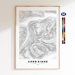 May include: A framed topographic map print of Càrn Eighe featuring black contour lines on a white background. The text Càrn Eighe, coordinates 57.288438 N, -5.114853 W, and 1183m are printed at the bottom. A colour palette strip is on the right.