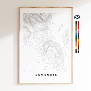 May include: A framed topographic map print of Ben Bowie, featuring contour lines in black against a white background. The print includes the name "BEN BOWIE" and coordinates. The frame is a light wood color.