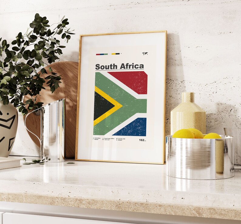 May include: A framed print with a vintage style graphic of the South African flag. The flag is red, yellow, green, black, and blue. The print is on a white background with the words "South Africa" and "162..." in black text.