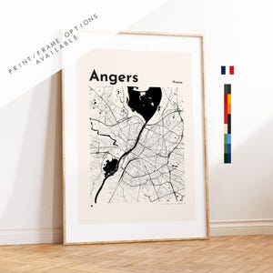 May include: A framed map print of Angers, France, in monochrome. The map shows the city's layout with streets and rivers. Text at the top reads "Angers" and "Print/Frame Options Available". The print is in a wooden frame.