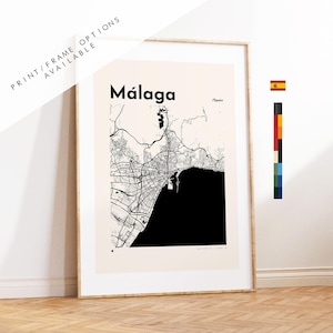 May include: A framed wall art print featuring a black and white map of Málaga, Spain. The map displays intricate street networks and a solid black area representing the coastline. The text reads Málaga and /Spain. A color palette strip is visible.