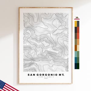 Puede incluir: Una impresión de mapa topográfico enmarcado del monte San Gorgonio con líneas de contorno negras sobre fondo blanco. El texto dice SAN GORGONIO MT. 34.0996 N, 116.8247 W 3506m. Una tira de paleta de colores vertical está a la derecha y una bandera de EE. UU. es visible.