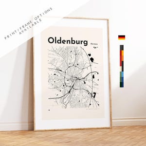 Op de afbeelding: Een ingelijste kunstdruk met een zwart-witte stadsplattegrond van Oldenburg, Duitsland. De kaart toont complexe wegennetwerken op een lichtbeige achtergrond met de tekst Oldenburg en /Germany in vetgedrukte zwarte letters aan de bovenkant.