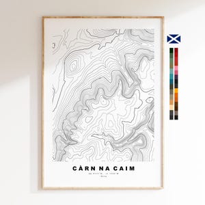 May include: A framed topographic map print featuring black contour lines on a white background. The text CÀRN NA CAIM is printed at the bottom with coordinates 56.9117°N, -4.1744°W and 861m. A vertical color palette strip and a Scottish flag icon are visible.