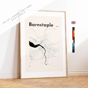 May include: A framed wall art print featuring a minimalist black and white map of Barnstaple, Devon. The design displays intricate road networks and a prominent river path on a light cream background. The text Barnstaple and Devon are printed.