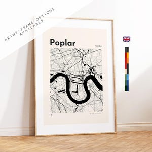 May include: Framed Poplar, London map art print. The black and white map features the area's street layout and the Thames River. The print is in a white frame and leans against a white wall. The text "Poplar" is at the top.