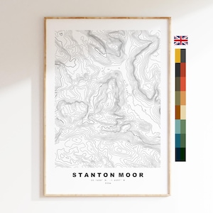 Puede incluir: Impresión enmarcada de un mapa topográfico de Stanton Moor. Líneas de contorno negras sobre fondo blanco. Incluye el nombre y las coordenadas del lugar. El marco es de color madera clara.