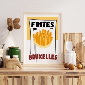Puede incluir: Un p&oacute;ster de estilo vintage con fondo amarillo y texto rojo y negro. El p&oacute;ster dice "Frites de Bruxelles 1985" y presenta una imagen de dibujos animados de una bolsa de papel de patatas fritas.