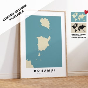 Könnte beinhalten: Ein gerahmter Druck einer Karte von Ko Samui, Thailand, mit der Umrisslinie der Insel in Beige auf einem blaugrünen Hintergrund. Der Text "KO SAMUI" ist unter der Karte gedruckt, zusammen mit den Koordinaten "9.5120° N, 100.0134° E". Der Druck ist in einem hellen Holzrahmen gerahmt. Das Bild zeigt auch eine Weltkarte mit der hervorgehobenen Insel in Schwarz und eine Weltkarte mit der hervorgehobenen Insel in Rot. Der Text "DIFFERENT COLOURS", "CUSTOM TEXT" und "CHOOSE A LOCATION" ist unter den Weltkarten gedruckt.