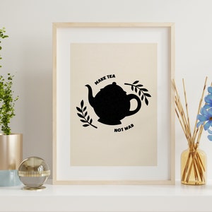 Pode incluir: Uma impressão emoldurada com uma silhueta preta de um bule de chá e o texto "Make Tea Not War" em um fundo bege.