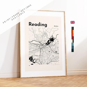 May include: A framed wall art print featuring a black and white street map of Reading, Berkshire. The map displays intricate road networks on a light beige background with the text Reading and Berkshire clearly printed at the top of the design.