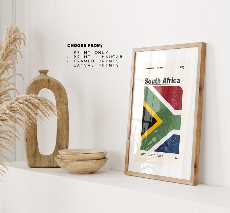 May include: A framed print of the South African flag with a white background and the text "South Africa" in black. The flag is red, yellow, green, and blue. The print is in a wooden frame.